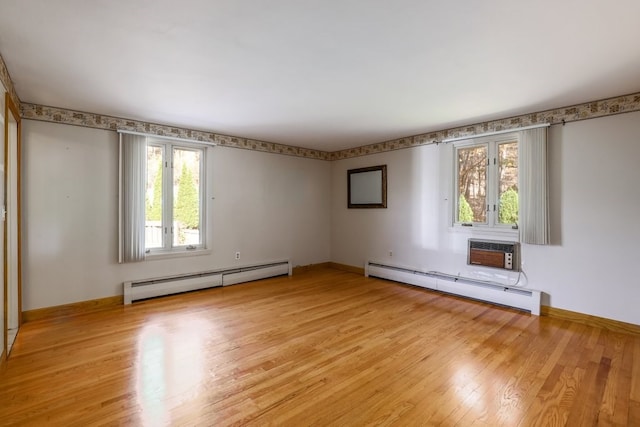 unfurnished room featuring an AC wall unit, a baseboard heating unit, and light hardwood / wood-style floors