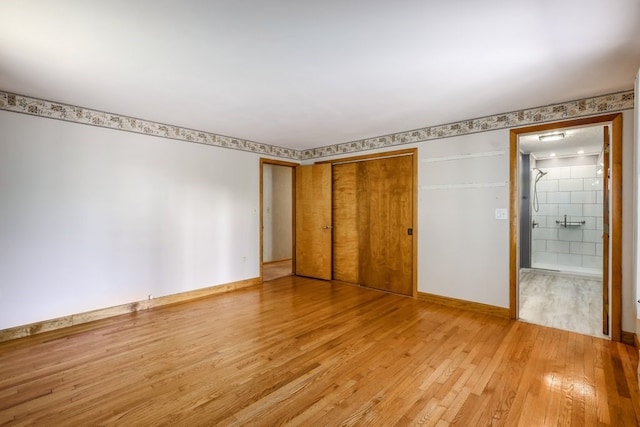 unfurnished bedroom with a closet, ensuite bathroom, and light wood-type flooring