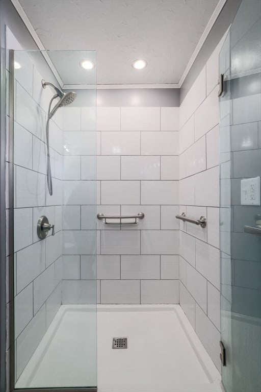 bathroom with ornamental molding and tiled shower