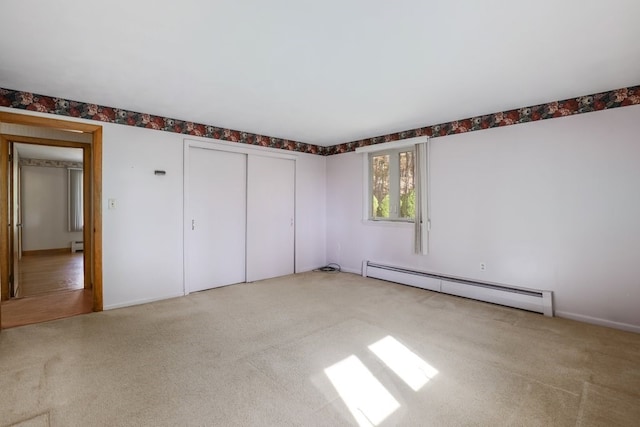 unfurnished bedroom featuring light carpet, a closet, and baseboard heating