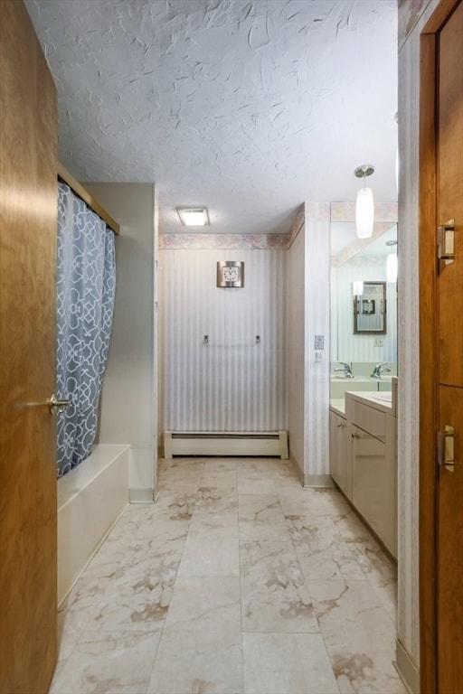 bathroom with vanity, a baseboard heating unit, shower / bath combo, and a textured ceiling