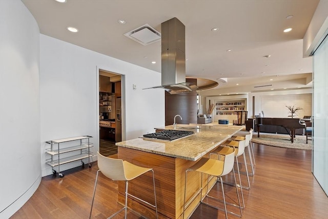 kitchen with wood finished floors, recessed lighting, a large island, stainless steel gas stovetop, and island range hood