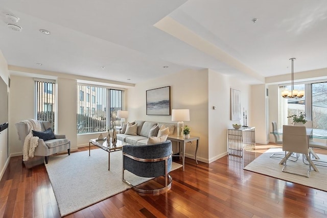 living room with baseboards, an inviting chandelier, and hardwood / wood-style flooring