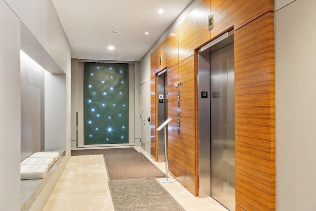 hallway with elevator and light colored carpet