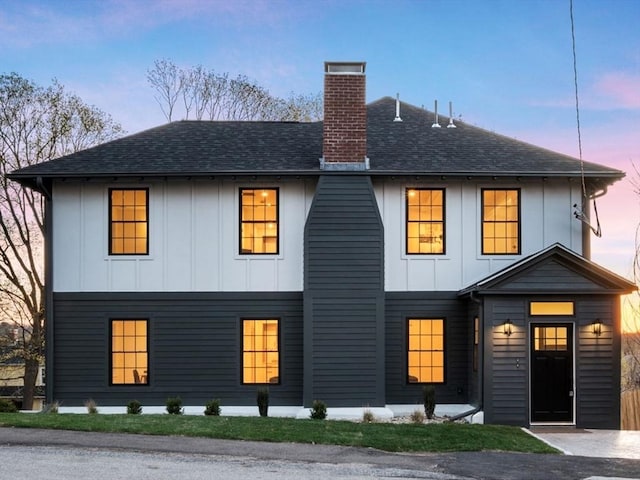 view of front of house featuring a chimney, board and batten siding, and a shingled roof