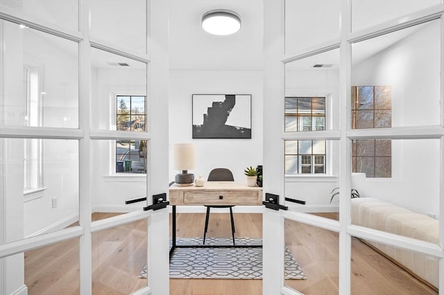 home office featuring light wood-type flooring, plenty of natural light, and french doors