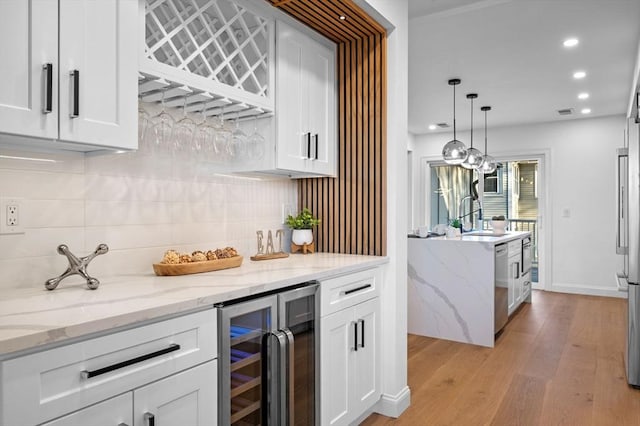 indoor dry bar with beverage cooler, backsplash, light wood-style floors, stainless steel dishwasher, and recessed lighting
