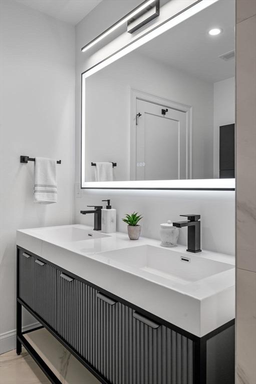bathroom with double vanity, recessed lighting, and baseboards