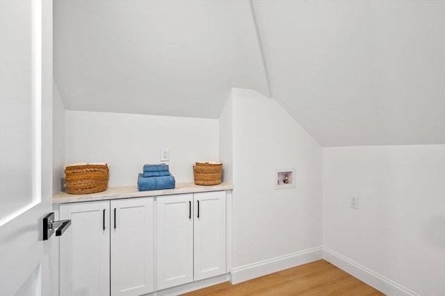 bonus room with vaulted ceiling, light wood-style flooring, and baseboards
