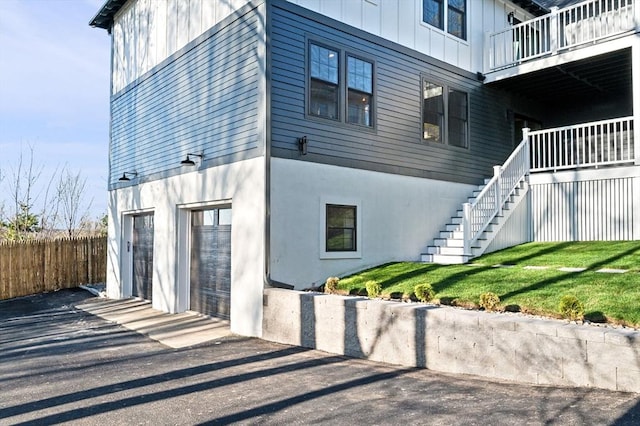 view of home's exterior featuring board and batten siding, stairs, a balcony, asphalt driveway, and a garage