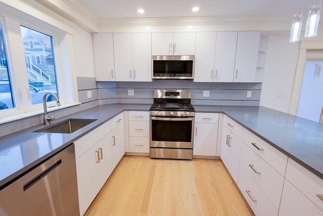 kitchen with a sink, open shelves, light wood-style flooring, white cabinets, and appliances with stainless steel finishes