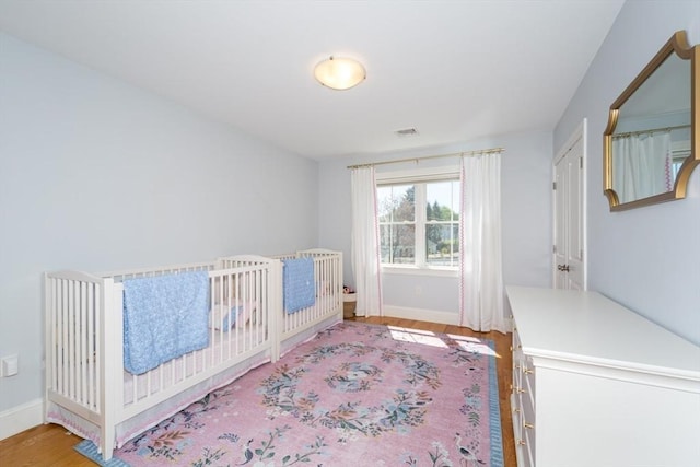70 Rockland St, Natick, MA 01760 - bedroom featuring baseboards, wood finished floors, and a crib