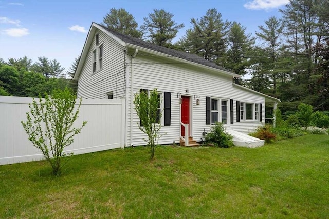 view of front of house featuring entry steps, a front lawn, and fence