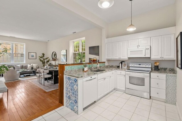 kitchen featuring white appliances, a sink, open floor plan, and white cabinetry