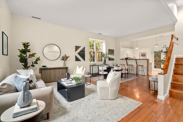 living room featuring stairway, light wood-type flooring, and baseboards