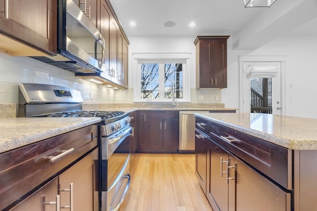 kitchen featuring tasteful backsplash, dark brown cabinets, appliances with stainless steel finishes, and light hardwood / wood-style flooring