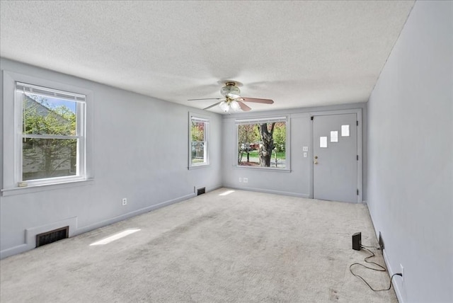 spare room featuring a wealth of natural light, a textured ceiling, and visible vents