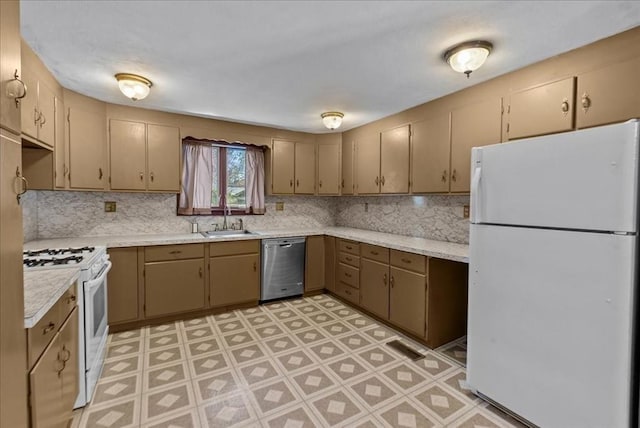 kitchen featuring white appliances, tasteful backsplash, a sink, and light countertops