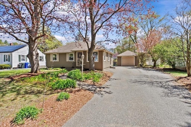 single story home with a garage, an outbuilding, and aphalt driveway