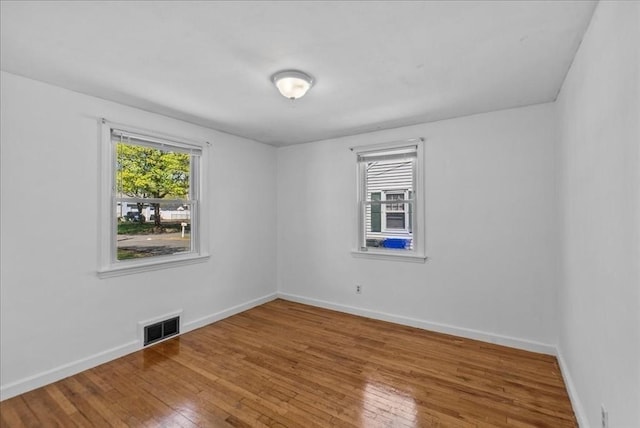 unfurnished room featuring baseboards, wood-type flooring, and visible vents