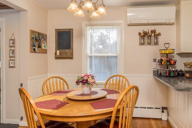 dining room featuring an inviting chandelier, ornamental molding, a wall mounted air conditioner, and light hardwood / wood-style flooring