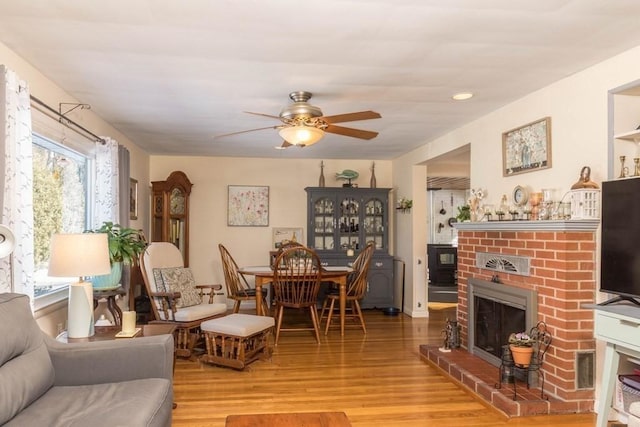 living room featuring light hardwood / wood-style flooring, a fireplace, and ceiling fan