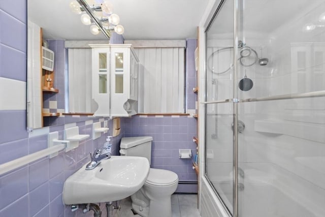 full bathroom with tile walls, baseboard heating, a sink, tile patterned floors, and toilet