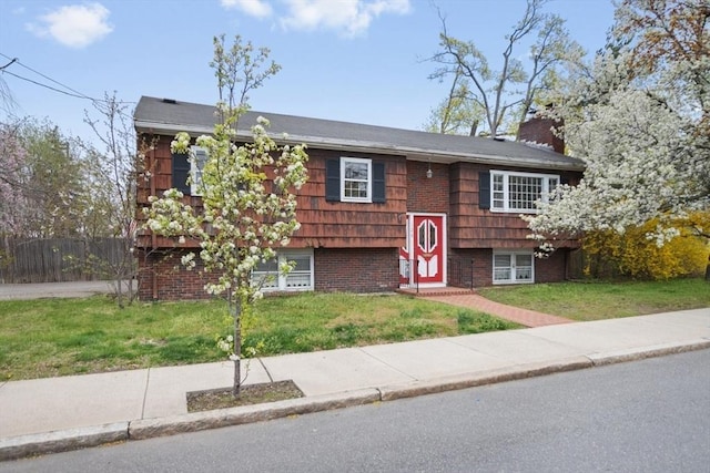 split foyer home with fence, a chimney, and a front lawn