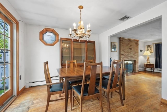 dining room featuring an inviting chandelier, a baseboard radiator, light wood finished floors, and visible vents