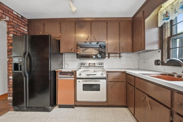 kitchen with light countertops, a sink, black appliances, and light floors