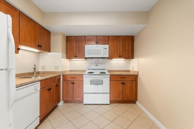 kitchen with white appliances, brown cabinetry, a sink, and decorative backsplash