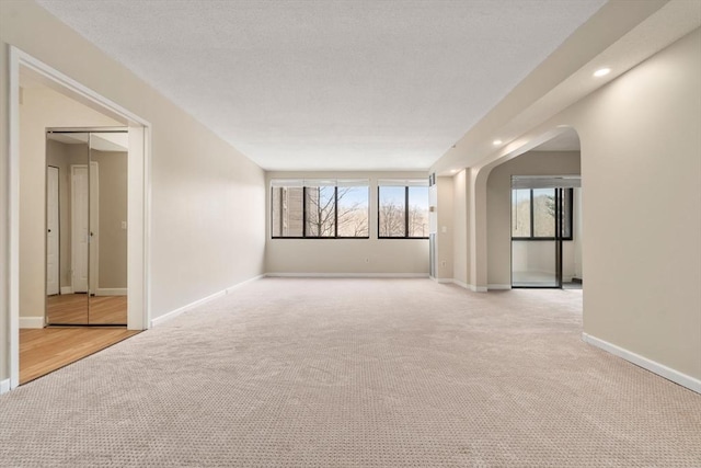 spare room with carpet, baseboards, arched walkways, and recessed lighting