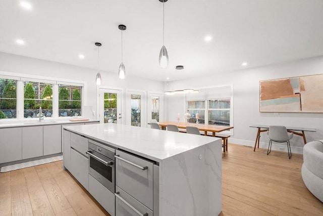 kitchen featuring a kitchen island, light wood finished floors, modern cabinets, and stainless steel oven