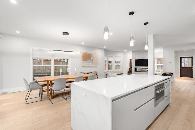 kitchen featuring light wood-type flooring, oven, pendant lighting, and a center island