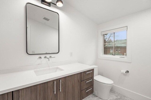 bathroom with vanity, visible vents, toilet, marble finish floor, and baseboards