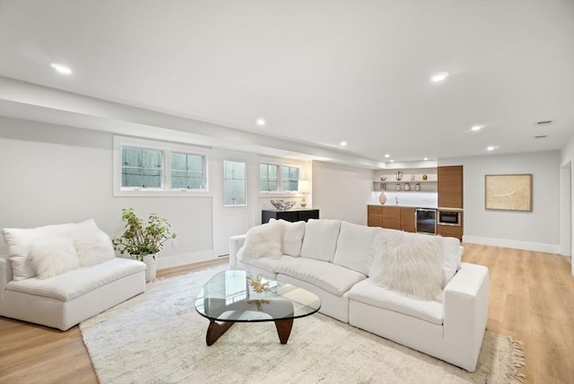 living room with baseboards, light wood finished floors, and recessed lighting