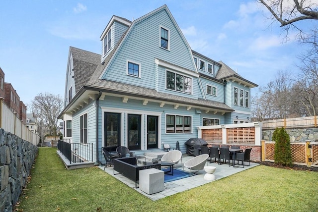 rear view of property featuring a yard, an outdoor living space, a gambrel roof, and roof with shingles