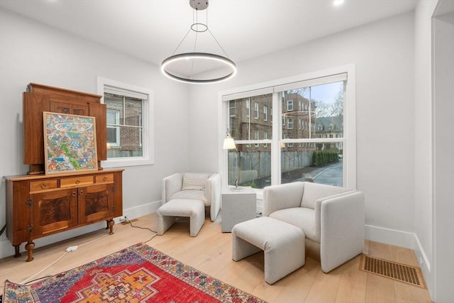 sitting room featuring visible vents, baseboards, and light wood-style flooring