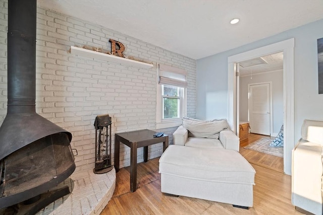 19 Borden, Scituate, MA 02066 - sitting room featuring attic access, light wood-style flooring, brick wall, and a wood stove