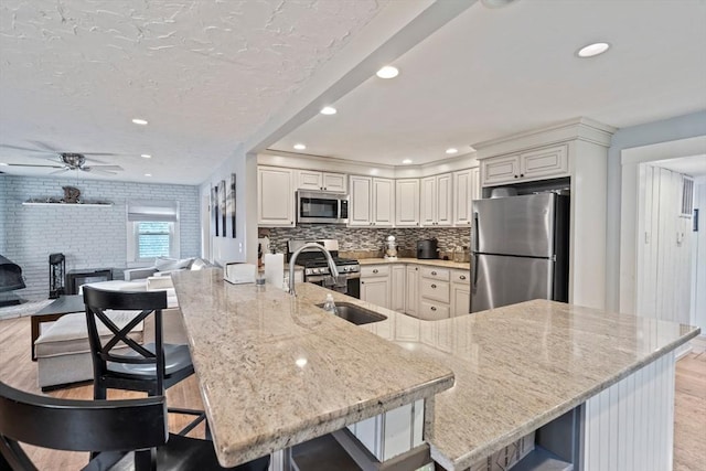 19 Borden, Scituate, MA 02066 - kitchen with appliances with stainless steel finishes, light wood finished floors, light stone counters, a breakfast bar area, and a peninsula