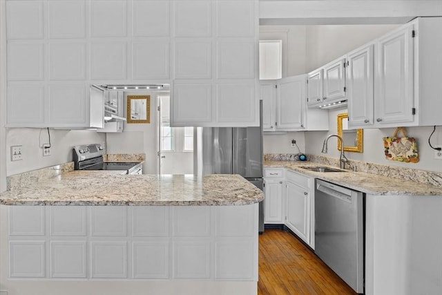 kitchen featuring sink, white cabinetry, stainless steel appliances, light hardwood / wood-style floors, and kitchen peninsula