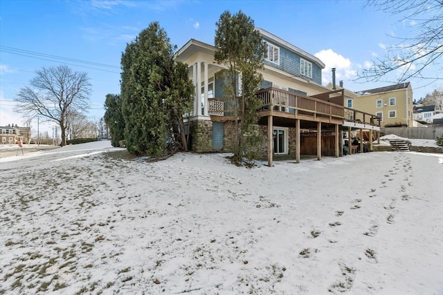 snow covered back of property featuring a wooden deck