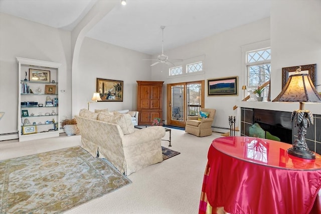 living room featuring ceiling fan, a towering ceiling, light colored carpet, and baseboard heating