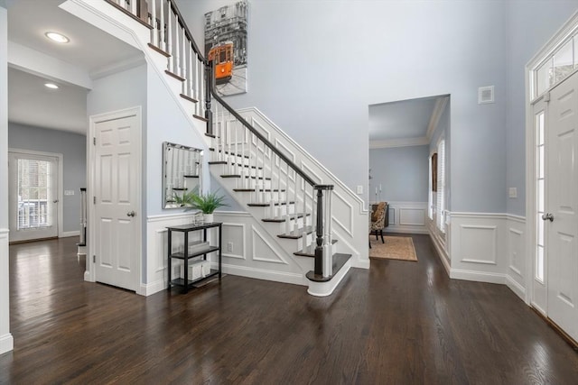 entryway featuring ornamental molding, dark hardwood / wood-style floors, and a towering ceiling