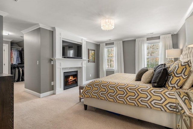 carpeted bedroom with a walk in closet, crown molding, and a closet