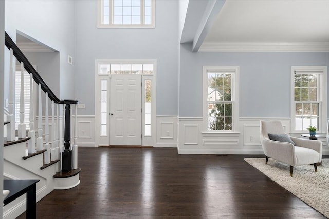 entryway with plenty of natural light, crown molding, and dark hardwood / wood-style floors