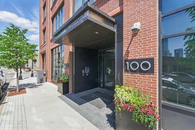 doorway to property featuring brick siding and a security system
