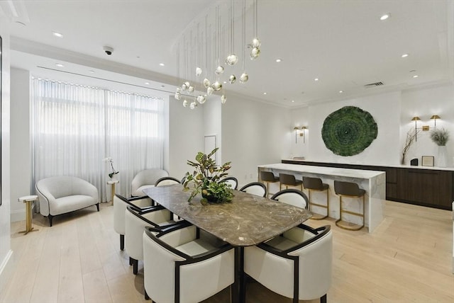 dining area featuring light wood-type flooring, ornamental molding, and recessed lighting