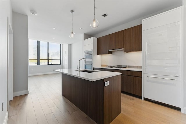 kitchen with gas cooktop, a sink, light countertops, modern cabinets, and baseboards
