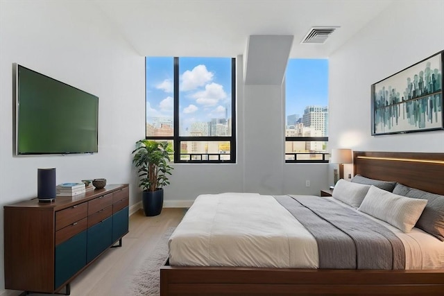 bedroom featuring a view of city, light wood finished floors, and baseboards